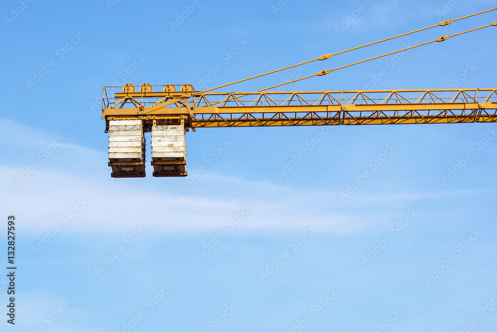 Part of yellow construction tower crane arm against blue sky