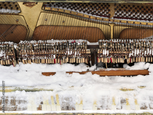 Vintage Piano musical instrument under the snow.