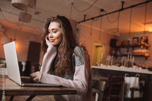 Happy young woman using a laptop in cafe