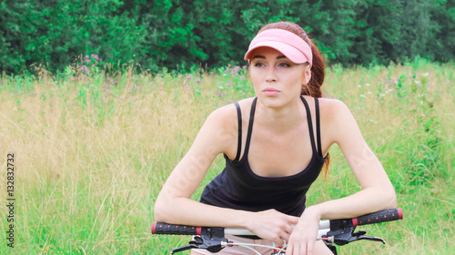 Beautiful girl on the nature leaned on his bike and looks though © singulyarra