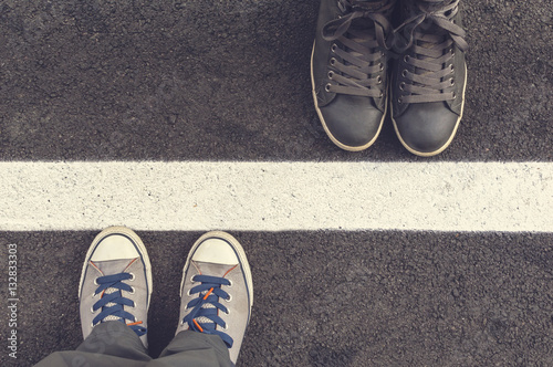 Two pair of sneakers on a asphapt road. photo