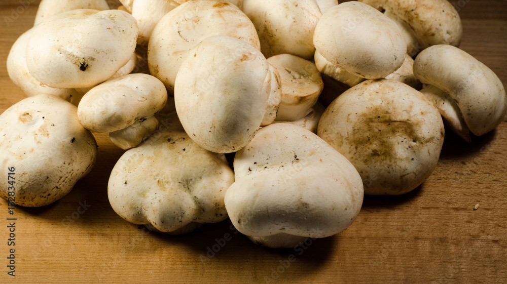White champignon mushrooms on a wooden table White champignon mushrooms on a wooden table