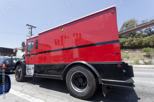 Side view of red armored truck in traffic. Horizontal. photo