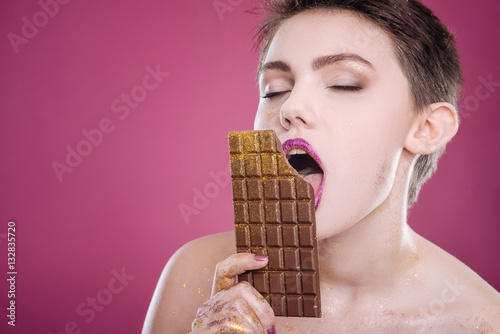 Delighted woman eating chocolate bar