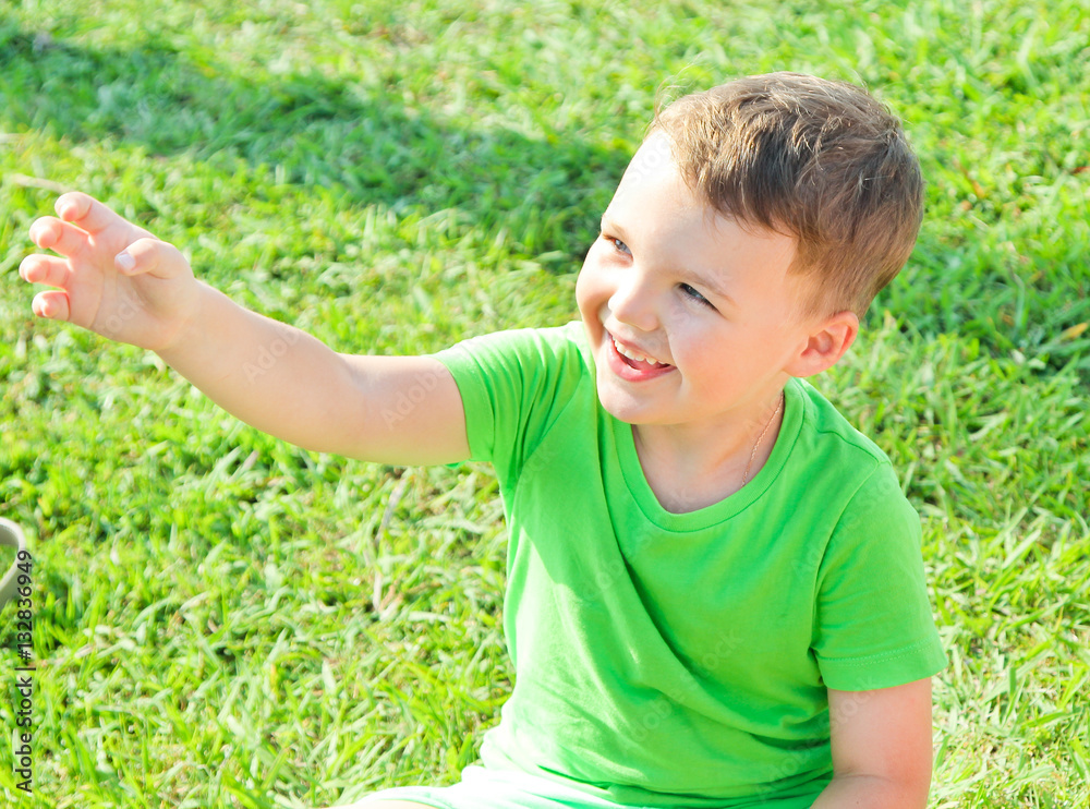 Cute boy pulling hand on the green grass. A boy dressed in green. Have fun time with family Cute boy pulling hand on the green grass. A boy dressed in green. Have fun time with family