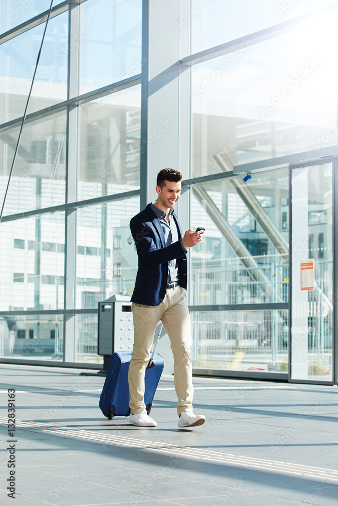 happy man walking with suitcase and phone in terminal happy man walking with suitcase and phone in terminal