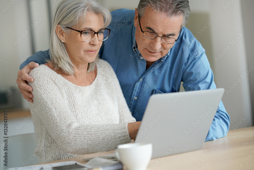 Senior couple at home using laptop computer