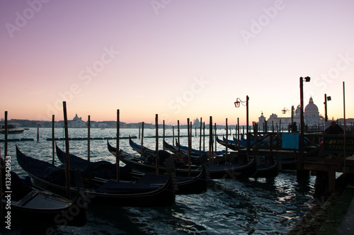 Traditional Venetian gondolas moored on the waterfront of Venice, Italy, with the Santa Maria della Salute Church in the background.