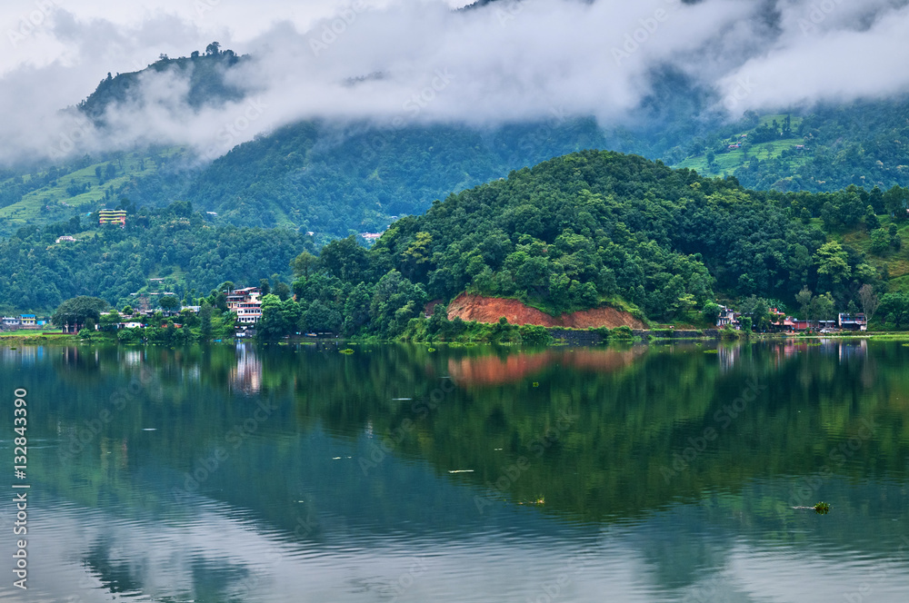 Green hills with bright lodges are reflected in quiet water of t