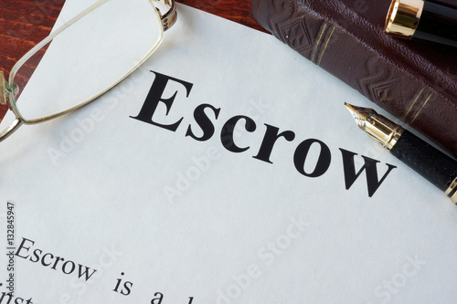 Paper with word Escrow and glasses on a table. photo