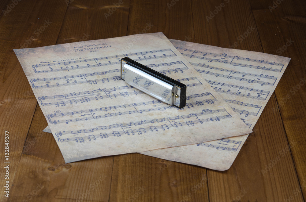 Silver harmonica and notes on the table wood Silver harmonica and notes on the table wood