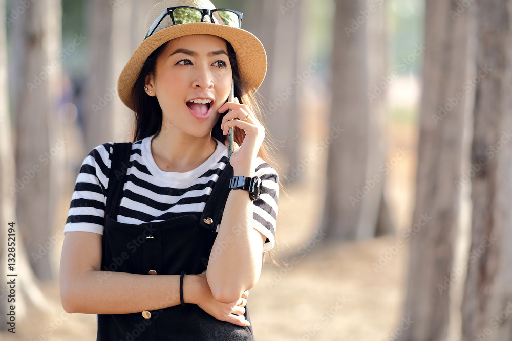 asian young girl talking on mobile phone with outdoor nature sunlight