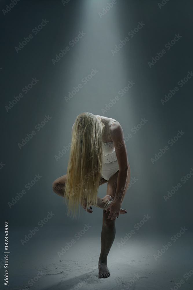 Fototapeta premium Woman dancer with long blond hair posing in the studio with low