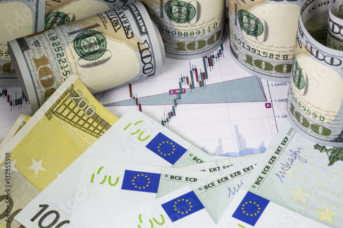 Euro dollar prices graph with japanese candlesticks. Euro bills, rolled hundred us dollars staying on the chart. Part of euro bills with  flag 100 and 200 euro banknotes . Macro image.
