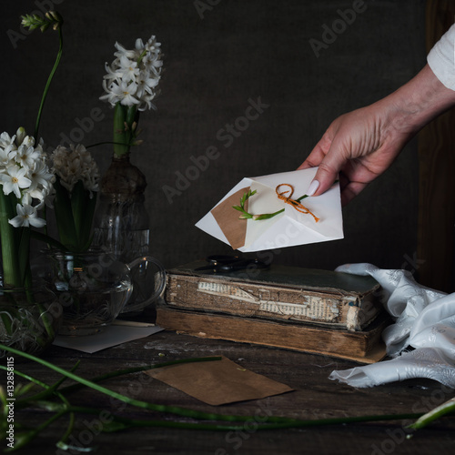 female hand holding out a letter with the envelope on dark background