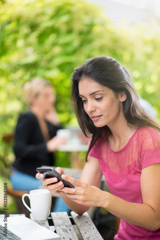 Cheerful woman sitting at a terrace cafe using a smartphone Cheerful woman sitting at a terrace cafe using a smartphone