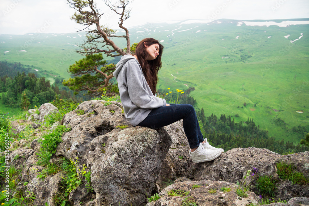 Beautiful woman sitting on mountain top and contemplating landsc Beautiful woman sitting on mountain top and contemplating landsc