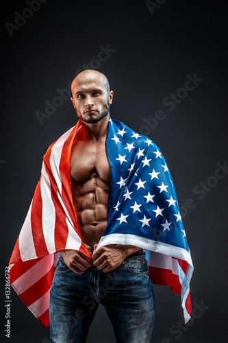 Portrait of bald strong bodybuilder in American flag in studio. Isolated. photo