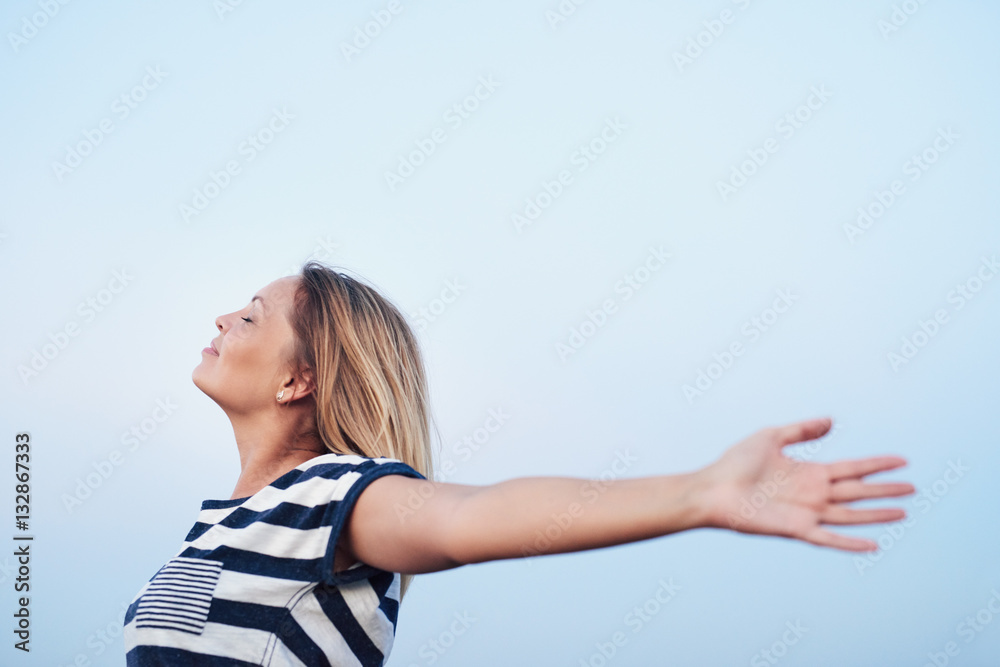 Fototapeta premium Young woman feeling free under a blue sky