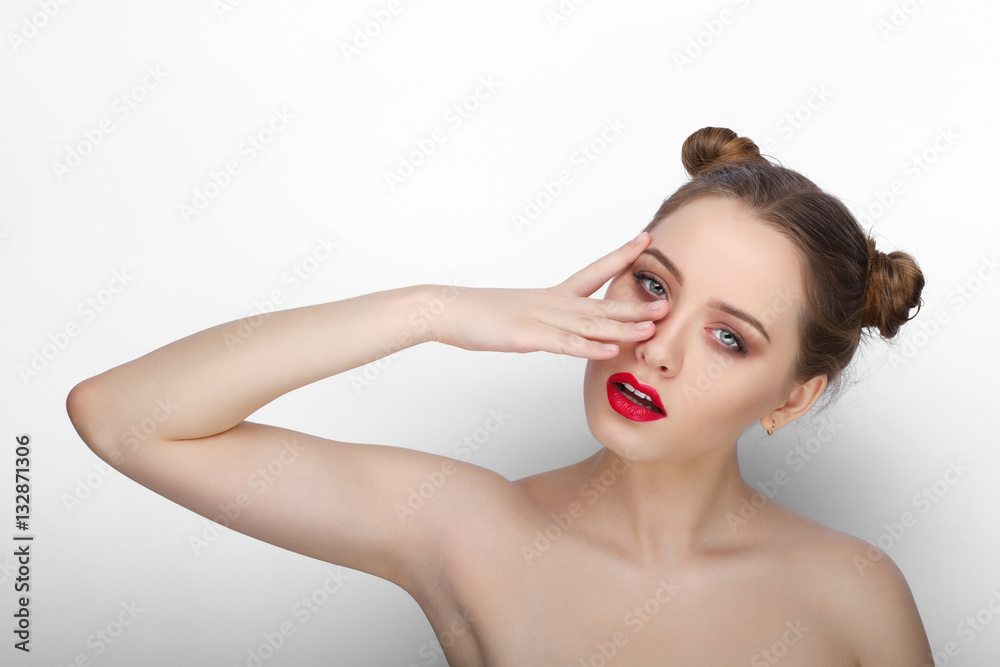 Naklejka premium Close-up beauty portrait of young playful woman with clean fresh healthy skin funny bun hairdo on white background