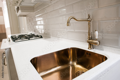 Angle view of kitchen sink with gold faucet