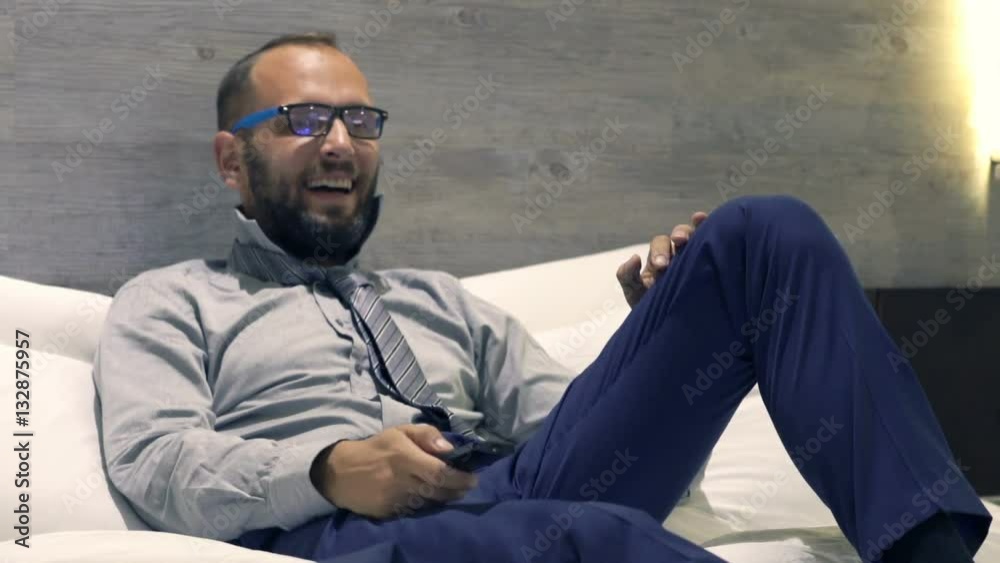 Young businessman watching TV lying on bed at night
Young businessman watching TV lying on bed at night