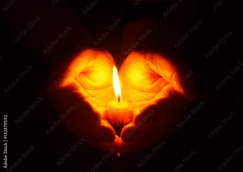 Hands and burning candle in dark