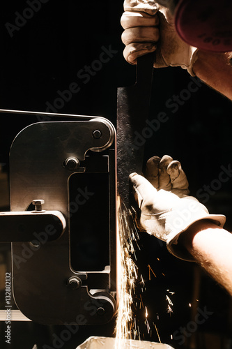 Person sharpening blade of knife on machine, close-up