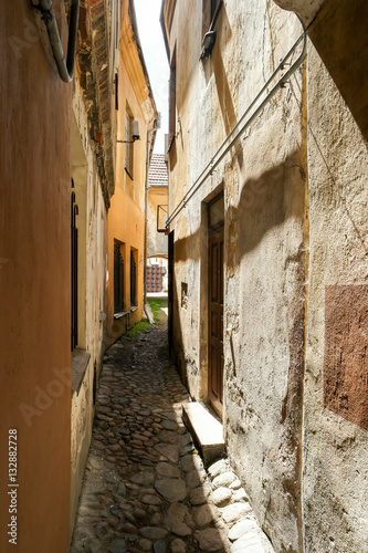 Narrow path between houses. Old walls and sunlight. One way to go.