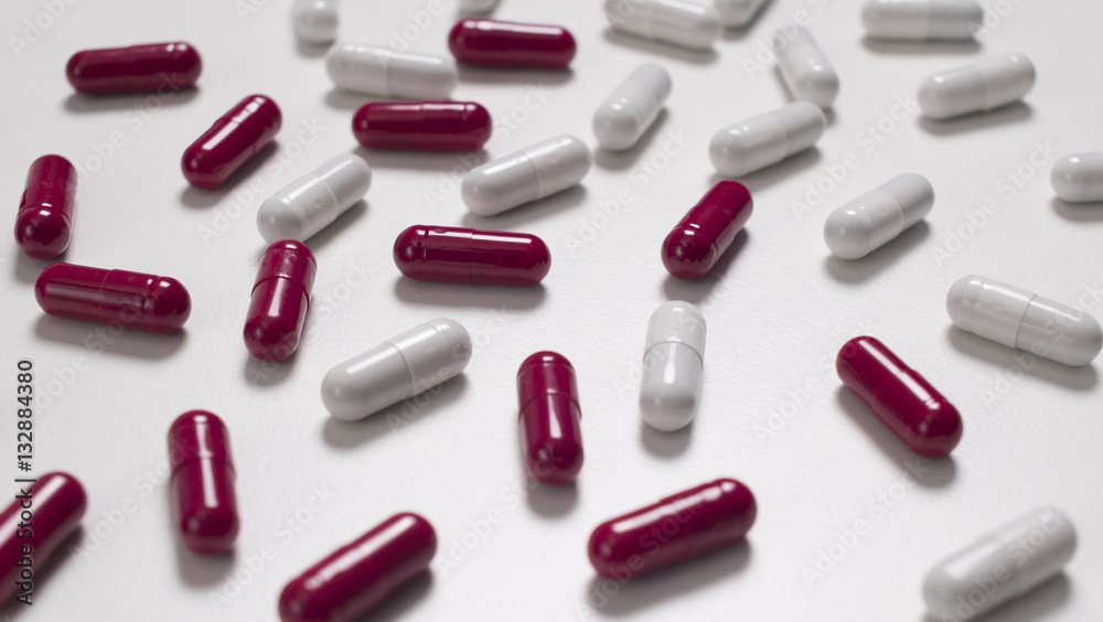 red and white capsules spread on a white background