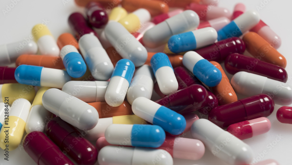 A lot of multi-colored capsules lay on a white background