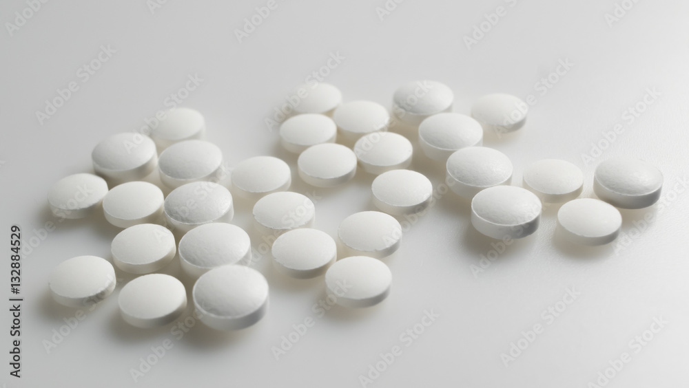 white round pills neatly stacked on a white background white round pills neatly stacked on a white background