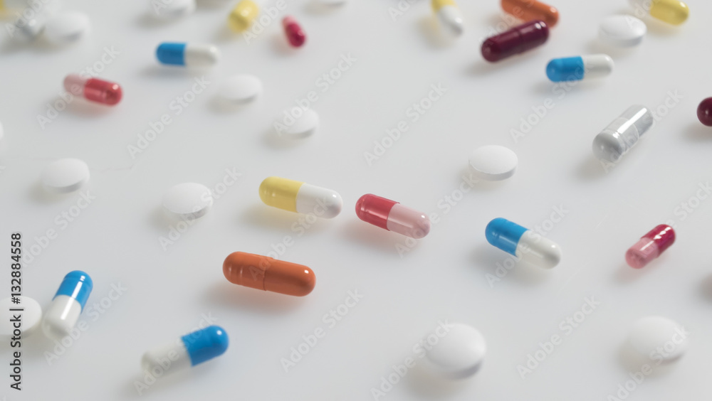 set of multicolored tablets and capsules arranged on white background close up set of multicolored tablets and capsules arranged on white background close up