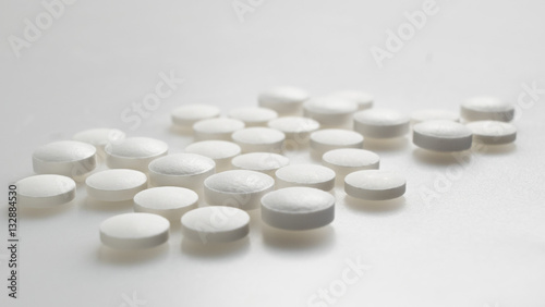 white round pills neatly stacked on a white background