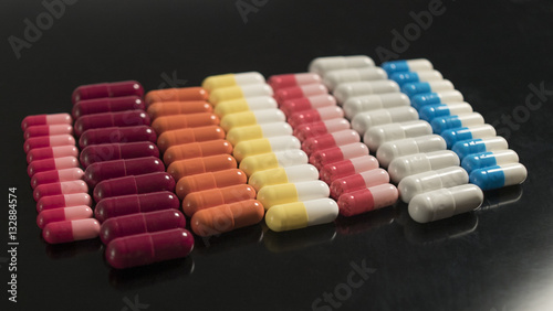 multi colored capsules neatly stacked on a black background