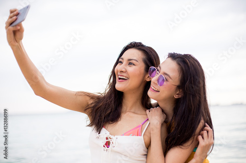 two friends take a selfie on the beach