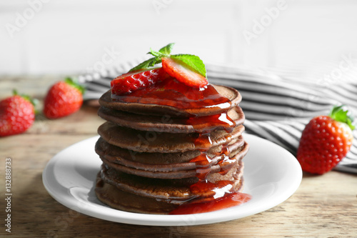 Delicious chocolate pancakes with strawberry on wooden table