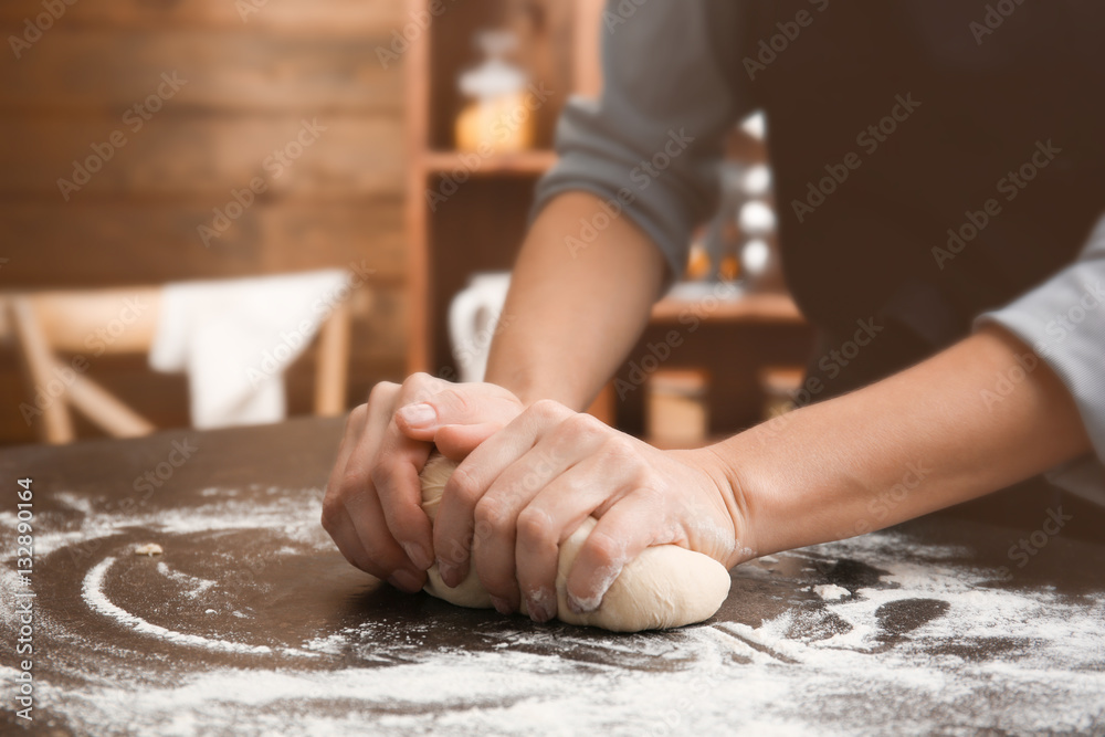 Young woman making dough in kitchen