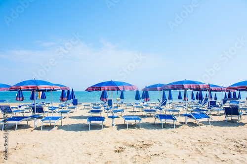 Adriatic Sea coast view. Seashore of Italy, summer umbrellas on sandy beach with clouds on horizon.