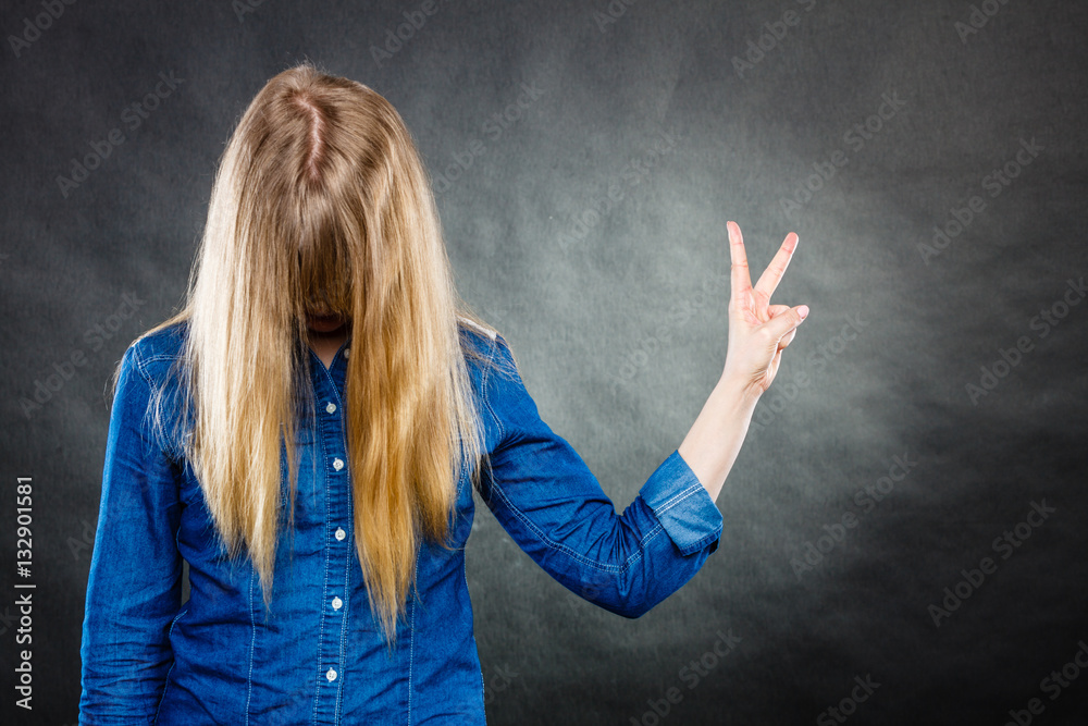 Blonde woman with covered face showing victory symbol. Blonde woman with covered face showing victory symbol.