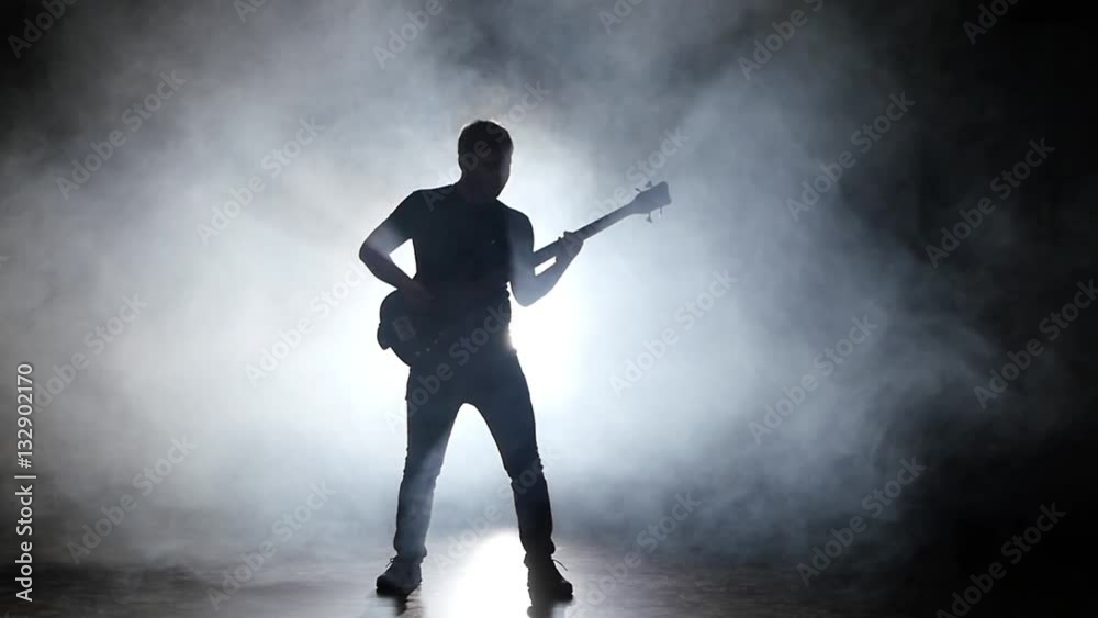 Man plays the bass guitar and jump to the music Man plays the bass guitar and jump to the music