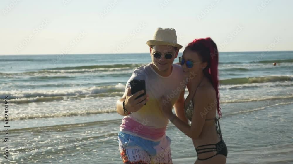 Beautiful lovers taking selfie on the beach and looking at photos Beautiful lovers taking selfie on the beach and looking at photos
