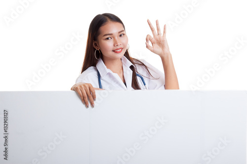 Young Asian female doctor show OK sign  behind blank white billb