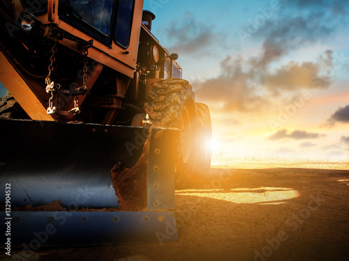 Silhouette Wheel loader Excavator with backhoe unloading sand at photo