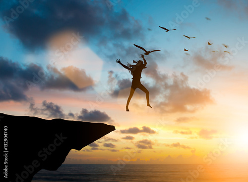 Silhouette Woman jumps off a cliff into the sea, the birds fly 