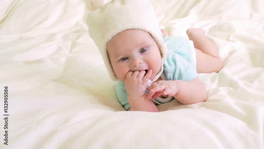 Baby plays with hat strings in bed. Baby plays with hat strings in bed.