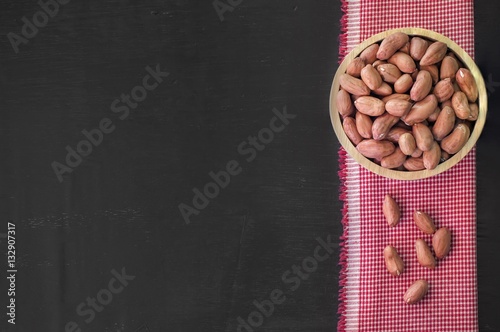 Raw peanuts or arachis in wooden bowl on table background photo
