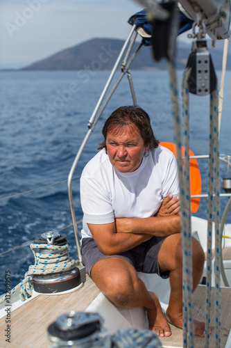 Male skipper is sitting on a sailing yacht. © De Visu