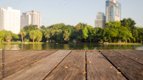 Defocus blur terrace wood and water, trees and building inside. Park view in city, natural background. Lumpini park, Bangkok Thailand.