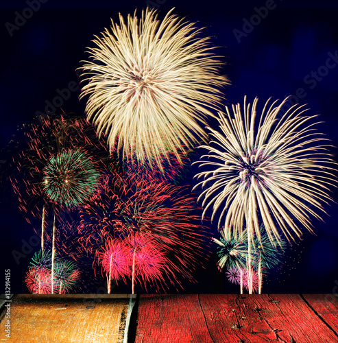 Wooden table with colorful firework celebration on dark backgrou